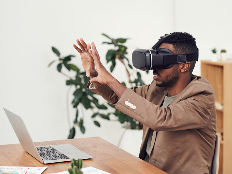 a man sitting at a desk wearing virtual reality goggles